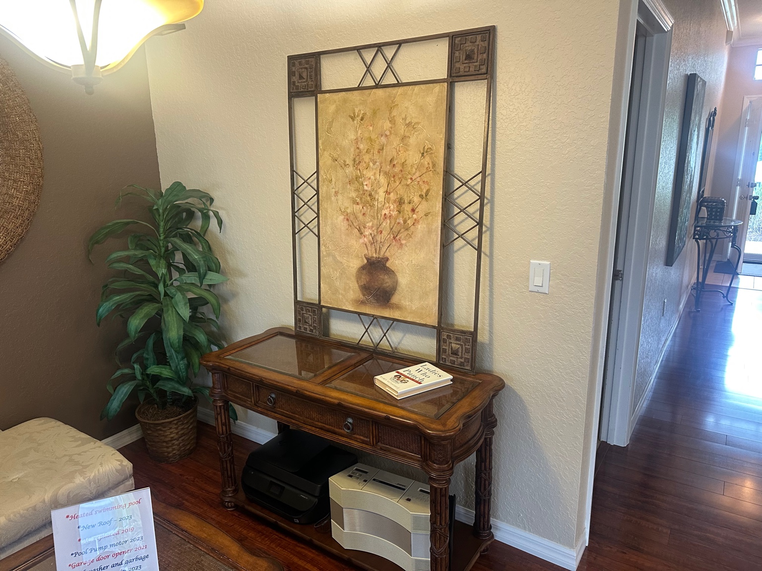Glass-top console table with rattan detailing and carved legs in an entryway of a Nashville home for sale
