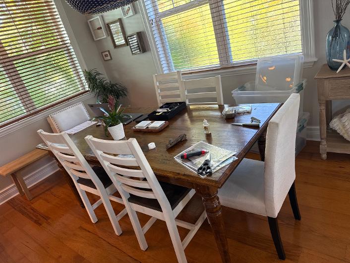 Solid wood farmhouse dining table with white ladder-back chairs and bench
