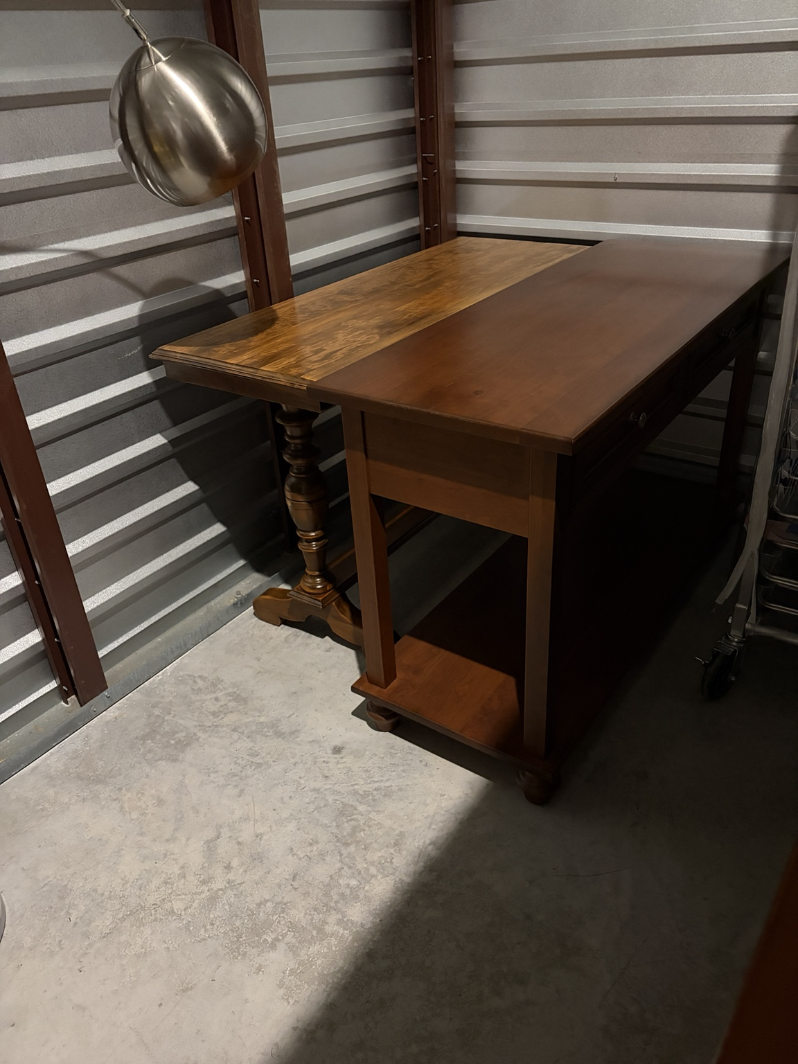 Solid wood writing desk with drawers and a pedestal side table inside a Nashville-area storage unit