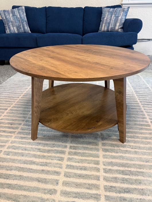 Round two-tier walnut coffee table in front of a navy sofa