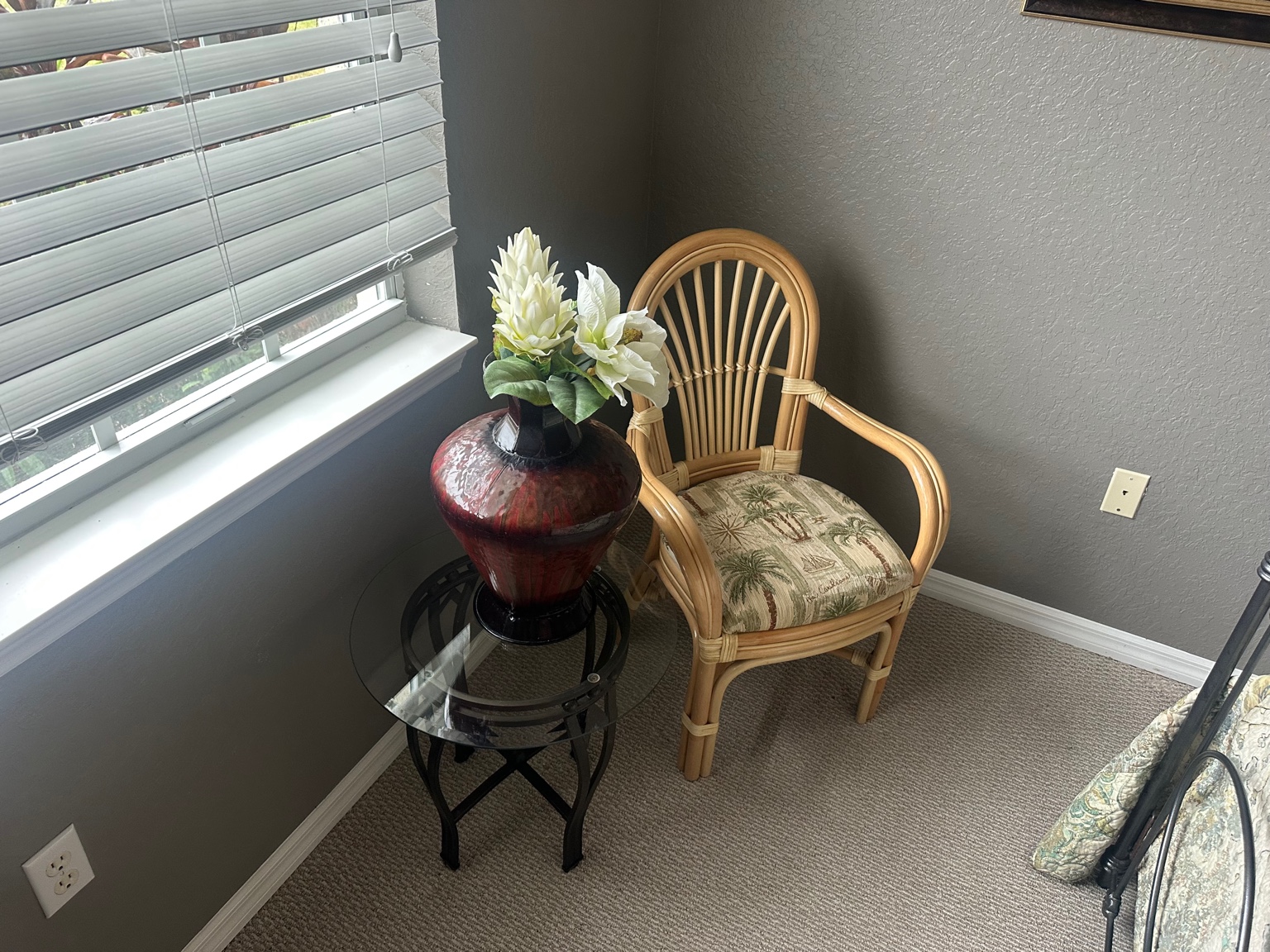 Rattan armchair with tropical print cushion beside a glass-top side table in a Nashville home